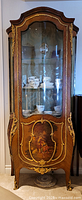 Full view of vitrine cabinet front with curved glass door, wood veneer and ormolu mounts
