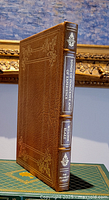 Side view of the leather bound book showing spine with title and gold embellishments