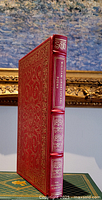 Photo of the book standing upright showing spine with gold embossed title and decorations.