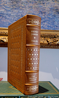 Front and spine view of leather bound Henry James Tales book with gold embossing and raised spine hubs against blue backdrop.