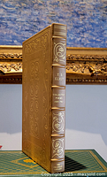 Front view of the leather bound book showing gold embossed floral decorations and title on spine