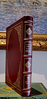 Front and spine view of the burgundy leather bound book with gold embellishments and raised hub.