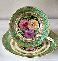 Front view of cup centered on matching saucer showing interior floral motif and gilt trim