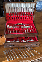 Full set arranged in two-tier wooden chest with red velvet lining and lower drawer open