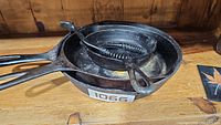 Top view of three cast iron pans stacked with coiled metal lid lifter inside the smallest pan
