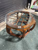 Side and angled view of the Mid-Century Modern walnut wood cocktail table showing the curved legs and lattice wood design under the thick round glass top which is resting on the base and removable.