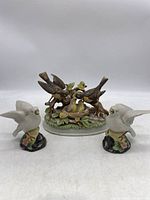 Three porcelain bird figurines including larger figurine of birds feeding baby birds and two smaller white bird figurines