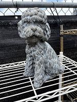 Front view of stone puppy sculpture showing detailed curls and facial features.
