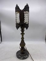 Full view of the vintage table lamp showing the marble base, brass ornamental body, and decorative panels with hanging crystals, some missing.