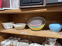 Overview of all six bowls on wooden shelf, showing nested pastel bowls and two patterned bowls
