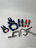 Photo showing the full assortment of clamps including plastic spring clamps, metal spring clamps with different colored handles, a metal C-clamp, and a locking C-clamp.