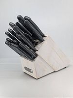 Front view of white painted wooden knife block filled with black-handled knives