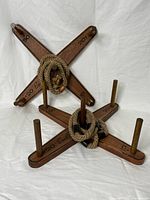Full view of two wooden cross bases with vertical dowels and several rope rings hanging on dowels. Marked with point values 20, 30, 50. Items arranged on white cloth background.