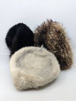 Three small hats arranged on white background: black fur hat, brown spiked fur hat, and light gray fur hat.