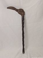 Full view of the hand-carved wooden cane handle showing the spiral shaft and bird head top