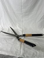 Photo showing the hedge shears with blades open, clear view of metal blades and wooden/black handles