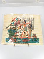 Front view of the papyrus painting laid flat and displayed on a stand, showing a dynamic scene of a human figure, birds, lotus plants, and hieroglyphs.