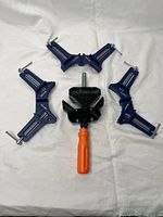 Top view of all four angle clamps including three blue Irwin Quick-Grip corner clamps and one black Pony 9180 clamp with orange handle.