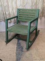 Front view of the green solid wood rocking chair showing slatted seat and backrest.
