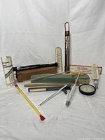 Full view of the collection of vintage thermometer, hydrometer and psychrometer instruments including units with wood boxes, metal tubes, and glass components.