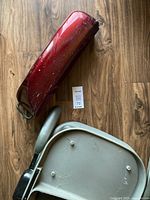 Three pieces for AutoGo 550 electric scooter: chassis base, red battery pack, and gray seat piece on a wood floor.