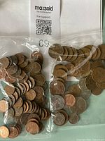 Two bags with mixed Canadian and British coins in various sizes and tones, primarily copper pennies and silver coins with visible tarnish and wear.