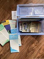 Plastic bin holding various travel maps including region, city, and camping maps mainly of U.S. locations.