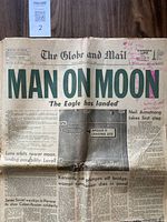 Front page of Globe and Mail newspaper with headline 'MAN ON MOON' and Apollo 11 landing site map, includes pink ink annotations and visible tears.