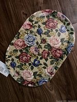 Full view of the vintage wooden oval serving tray with multicolored floral pattern on the surface.