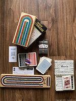 Wooden cribbage board set with box, playing cards, pegs, and instructions.