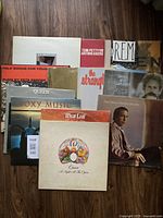 Full lot of 13 vinyl LPs arranged on a wood floor showing album artwork including Queen 'A Night At The Opera', Meat Loaf 'Bat Out of Hell', Roxy Music and others.