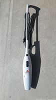 Upright Bissell handheld electric vacuum cleaner with cord wrapped on handle.