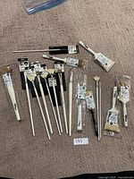 Full spread of all paint brushes laid out on carpet, showing variety of sizes and shapes