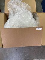 Open cardboard box containing the bubble wrap roll partially visible.