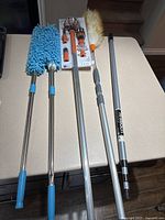 Overview of all dusters, lightbulb changing kit, and extension poles laid out on surface