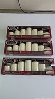 Three boxed sets of flameless LED candles with remote controls and batteries inside.
