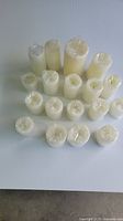 Group of 17 flameless wax candles wrapped in bubble wrap, arranged on a white surface showing various heights and realistic wax texture.