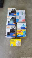Photo showing all boxes in the lot including HDX Extra Thick Drum Liners, HDX Multi-Purpose Clear Bags, Glad Blue Large Garbage Bags, and transparent multi-use recycling bags.