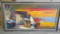 Full view of framed oil painting showing vibrant coastal landscape at sunset with ships, buildings, and mountains.