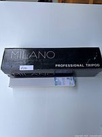 Photo showing Milano professional tripod box and JJC camera umbrella box on a white surface, confirming both items are brand new and boxed.