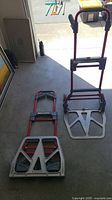 Two Milwaukee folding aluminum hand trucks, one folded, one upright showing platform and wheels.