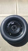 Photo of the entire 17 inch temporary spare tire mounted on a black steel rim, clearly showing tread and rim.