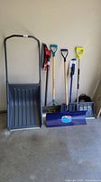 Full view of lot showing six snow removal tools including a large pusher, snow shovels, ice scraper, and broom
