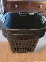 Front perspective view showing height, shape, and handle design of the black laundry basket.