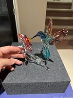 Multicolored crystal hummingbird figurine with flower displayed on foam block