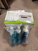 Box of InvisiClean Pro Elite Ultrasonic Cleaner and three bottles of cleaning concentrate sealed in plastic bags.
