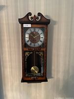 Full view of the wooden Citizen wall clock hanging on a wall showing entire clock body and pendulum window.
