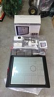 Photo of all included items of Bios Atmosphere 2.0 weather station kit displayed together on floor including main touchscreen display, sensors, cables, manual, and box.