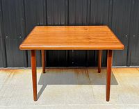 Front view of square teak coffee table showing rounded edges and four tapered legs.