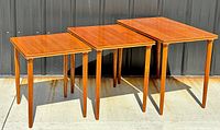 Three teak nesting tables grouped together showing full set